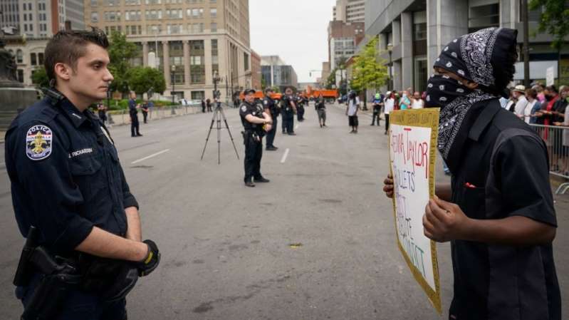 A protester confronts a police officer during a rally against the death of Breonna Taylor and other forms of racial injustice in Louisville on Saturday [Bryan Woolston/Reuters]